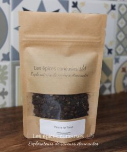 Poivre de Timut en sachet kraft, épices exotiques sur fond de carreaux colorés. Parfait pour agrémenter vos plats.