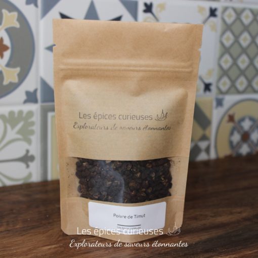 Poivre de Timut en sachet kraft, épices exotiques sur fond de carreaux colorés. Parfait pour agrémenter vos plats.