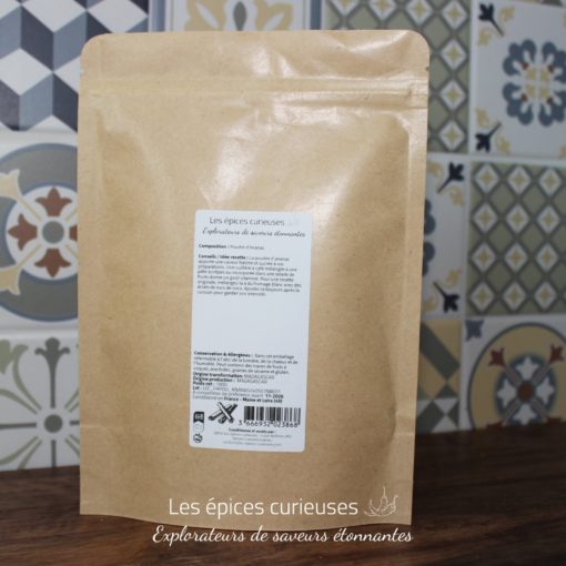 Paquet kraft d'épices Les épices curieuses avec de la poudre d'ananas, sur fond de carreaux colorés.