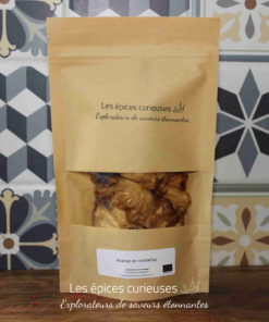 Sachet de rondelles d'ananas séchées, produit par Les Épices Curieuses, devant un carrelage coloré.