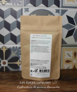 Sachet d'épices variées devant un mur de carreaux décoratifs, parfait pour rehausser vos plats avec des saveurs uniques.