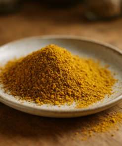 Assiette en céramique avec poudre de curcuma dorée, sur une table en bois rustique.