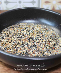 Mélange de graines varié dans un bol noir sur une table en bois, idéal pour cuisine et pâtisserie.