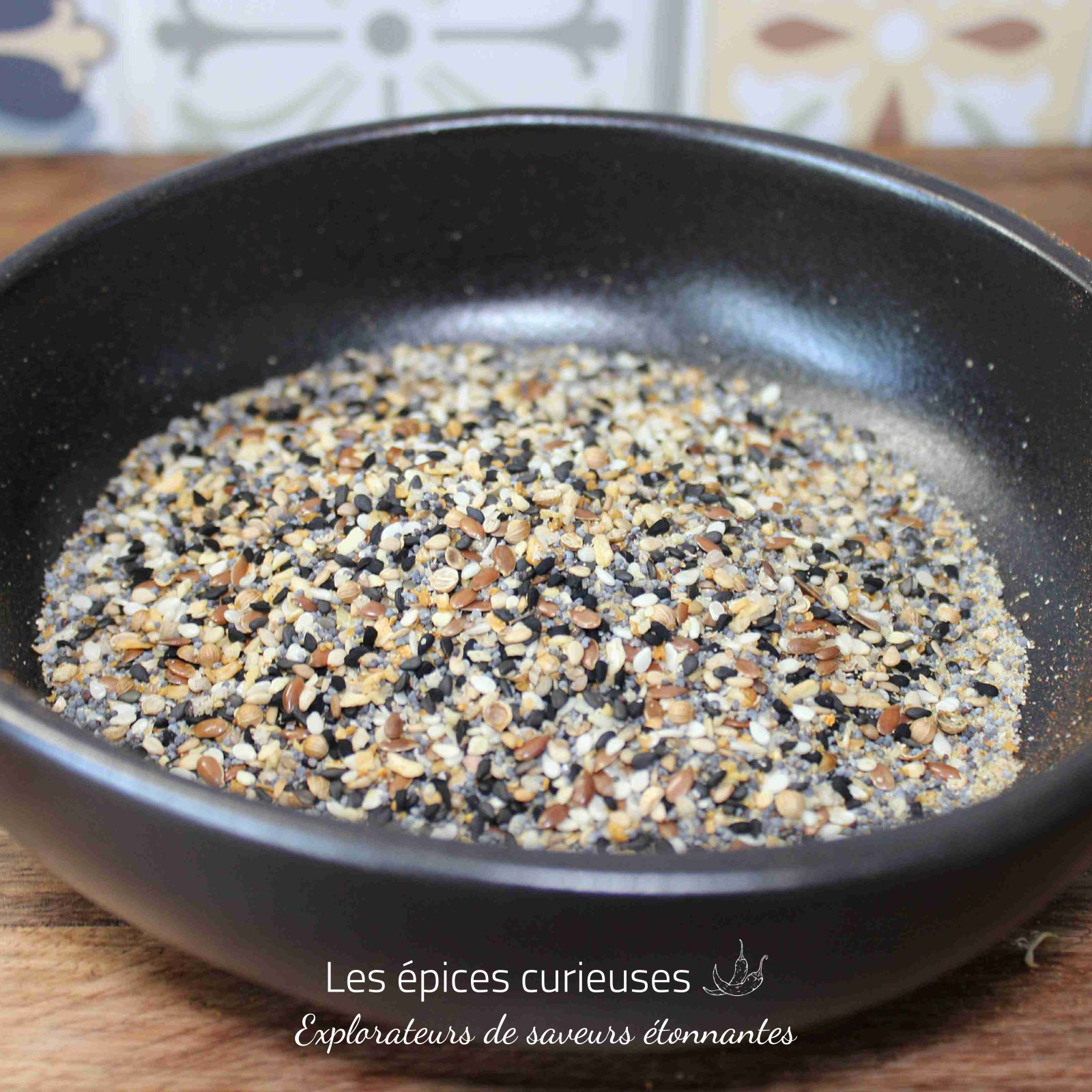 Bagel Twist Oriental (2) Mélange de graines varié dans un bol noir sur une table en bois, idéal pour cuisine et pâtisserie.