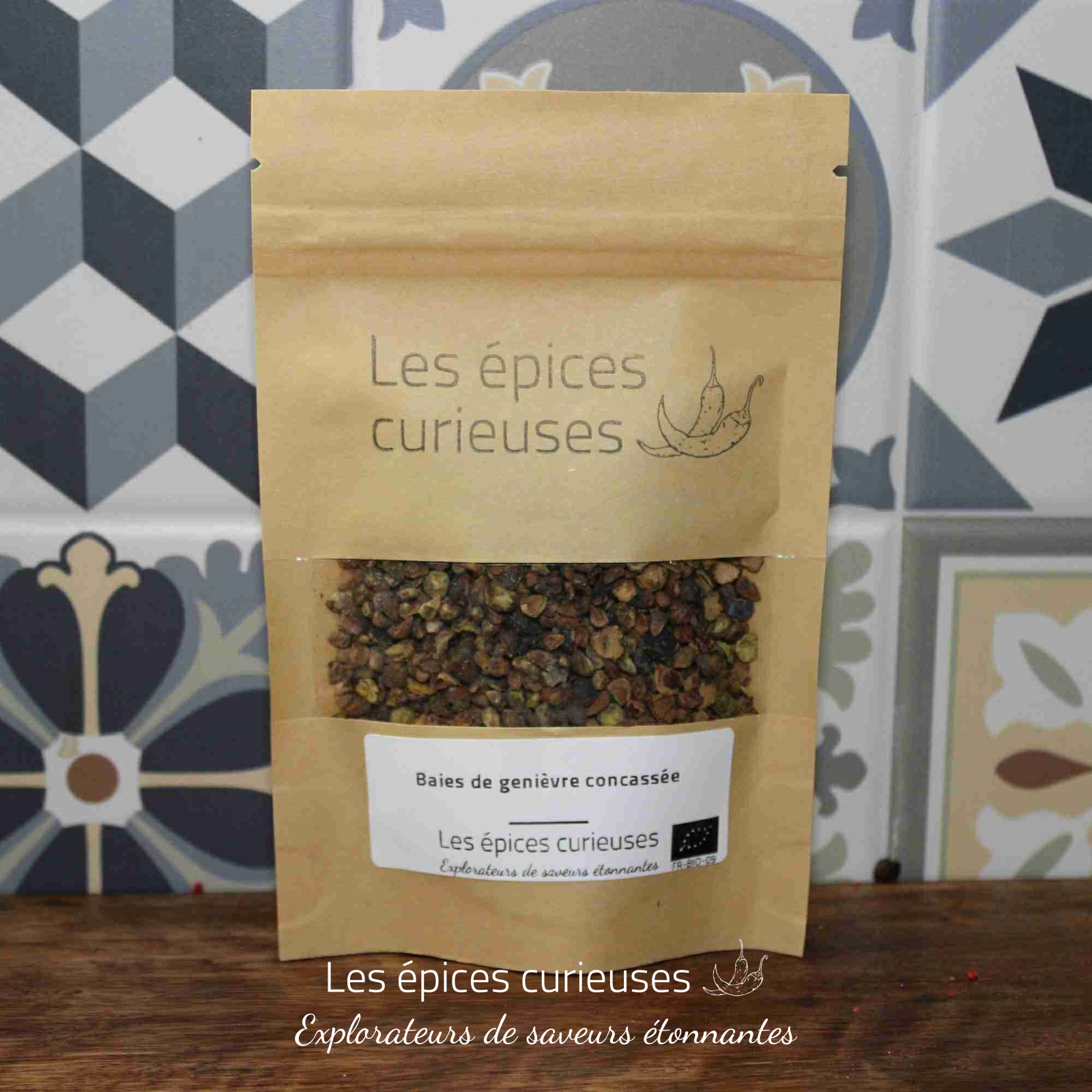 Baies de genievre concassé (2) Paquet de baies de genièvre concassées de Les épices curieuses sur fond de carreaux décoratifs.