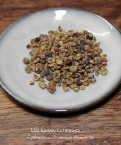 Assiette de graines de cardamome séchées sur une table en bois, vue rapprochée pour un usage culinaire ou aromatique.