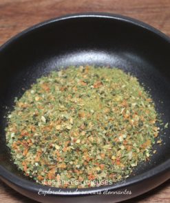 Mélange d'épices séchées dans un bol noir sur une table en bois, prêt pour la cuisine.