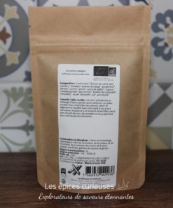 Sachet d'épices biologiques multicolores, fond fleuri. Composition variée: cumin, carottes, gingembre. Produit artisanal.