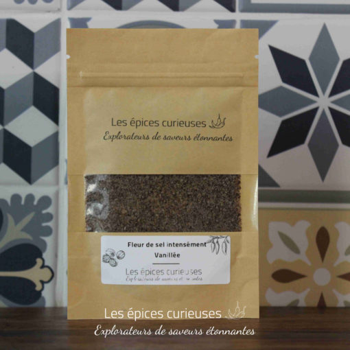 Sachet de fleur de sel vanillée Les épices curieuses devant un carrelage à motifs noirs et gris.