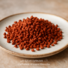 Pile de graines d'achiote rouges sur une assiette blanche, utilisée comme colorant naturel ou épice.