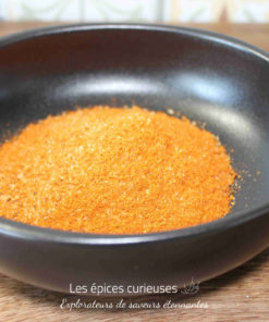 Assaisonnement orange vif dans un bol noir, idéal pour relever vos plats et recettes préférées.