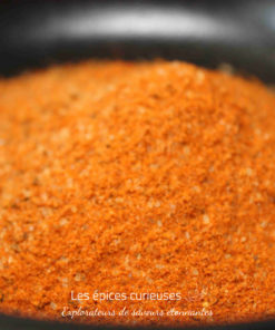 Épices rouges en poudre dans un bol noir, prêtes pour la cuisine savoureuse et aromatique.