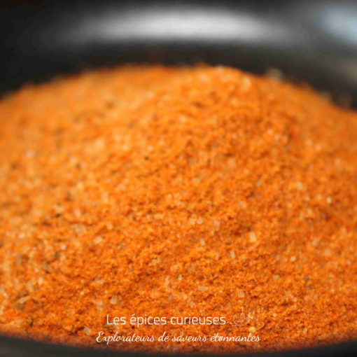 Épices rouges en poudre dans un bol noir, prêtes pour la cuisine savoureuse et aromatique.
