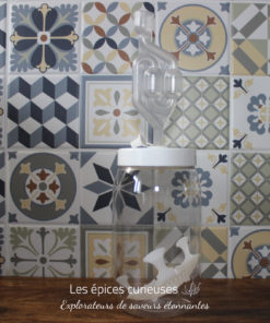 Fermenteur en verre avec barboteur sur fond de carreaux colorés, prêt pour la fermentation maison.