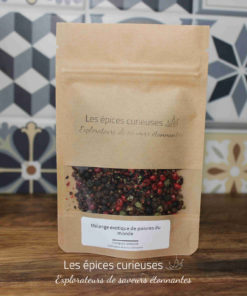 Sachet de Mélange exotique de poivres du monde par Les Épices Curieuses, devant un mur de carreaux décoratifs.