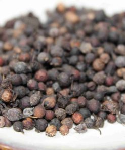 Poivre noir en grains sur une assiette blanche, épice essentielle pour rehausser les saveurs culinaires.