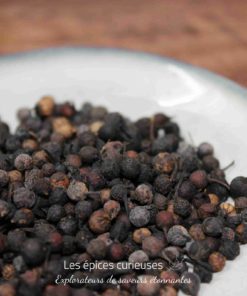 Baies séchées épicées sur assiette blanche, idéal pour assaisonner plats exotiques et créoles.