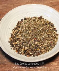 Assortiment d'épices dans un bol blanc sur une table en bois, parfait pour la cuisine maison.