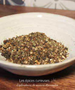 Assiette de mélange d'épices artisanales sur une table en bois pour une cuisine savoureuse et aromatique.