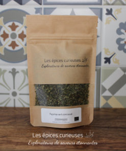 Sachet de paprika vert concassé par Les épices curieuses, sur fond de carrelage décoratif.