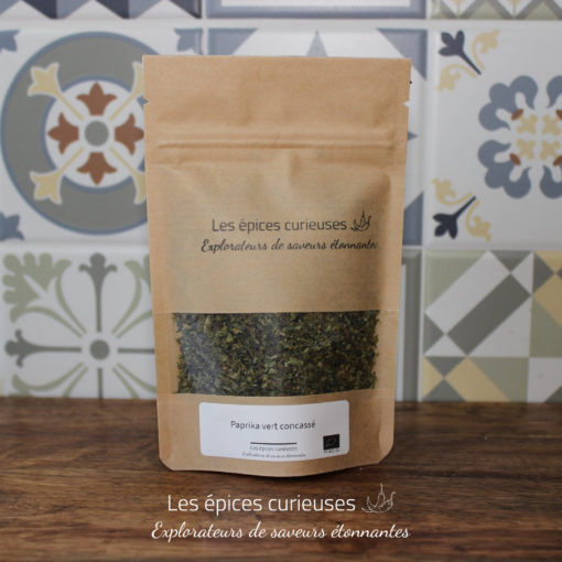 Sachet de paprika vert concassé par Les épices curieuses, sur fond de carrelage décoratif.