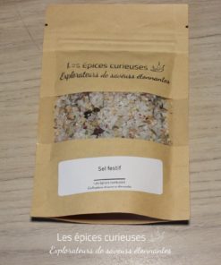 Sachet de sel festif Les Épices Curieuses sur une table en bois, saveurs uniques pour vos plats.