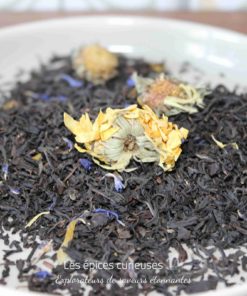 Mélange de thé noir avec des fleurs séchées dans une assiette blanche, prêt pour l'infusion.