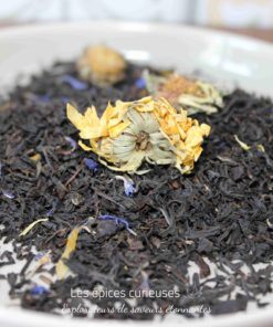Mélange de thé noir avec fleurs séchées dans une assiette blanche, prêt pour l’infusion.
