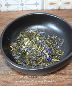 Bol de tisane aux fleurs séchées colorées sur planche en bois, fond carrelé.