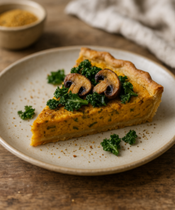 Part de tarte salée aux champignons et chou frisé sur une assiette en céramique, fond en bois rustique.