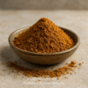 Bol en céramique rempli de poudre d'épices brun orangé sur une surface en pierre.