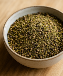 Bol de poivre vert moulu sur une table en bois, capturant la texture et les nuances naturelles de l'épice.