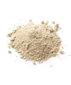 Poudre beige en vrac sur fond blanc, utilisée en cuisine pour diverses préparations alimentaires.
