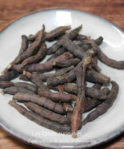 Gousses de poivre long sur une assiette blanche, épice aromatique utilisée en cuisine pour son goût unique.