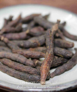 Gousses de poivre long sur une assiette blanche, épice aromatique utilisée en cuisine pour son goût unique.