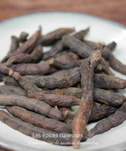 Gousses de poivre long sur une assiette blanche, épice aromatique utilisée en cuisine pour son goût unique.