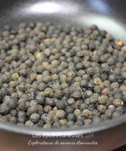 Grains de poivre noir entiers dans une poêle, prêts à être utilisés en cuisine pour aromatiser vos plats.