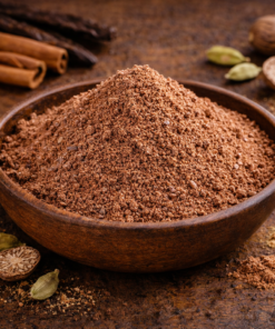Bol de poudre d'épices mélangées sur une table en bois avec bâtons de cannelle et noix de muscade. Parfait pour cuisiner.