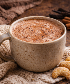Tasse de chocolat chaud crémeux sur fond d'automne, accompagnée de biscuits sablés.