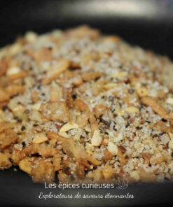 Mélange de noix concassées et épices sur fond noir, idéal pour ajouter du croquant et de la saveur aux plats.