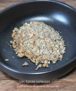 Mélange de noix concassées dans un bol noir sur une surface en bois.