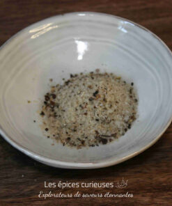 Assiette de sel de mer assaisonné, posée sur une table en bois. Parfait pour rehausser vos plats culinaires.