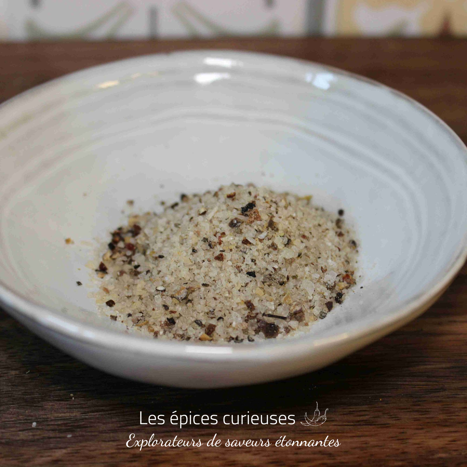 Fleur de sel aux poivres du monde (3)(1) Bol en céramique contenant un mélange de sel et d'épices sur une table en bois.