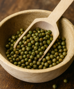 Boulettes de poivre vert dans un bol en bois avec une cuillère, détail de cuisine épicée.