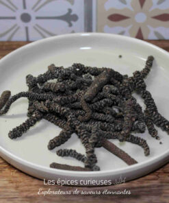 Assiette de poivre long d'Inde entier sur une table en bois, idéale pour épicer vos plats et découvrir de nouvelles saveurs.