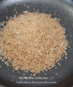 Un tas de sucre brun naturel sur une assiette noire lisse.