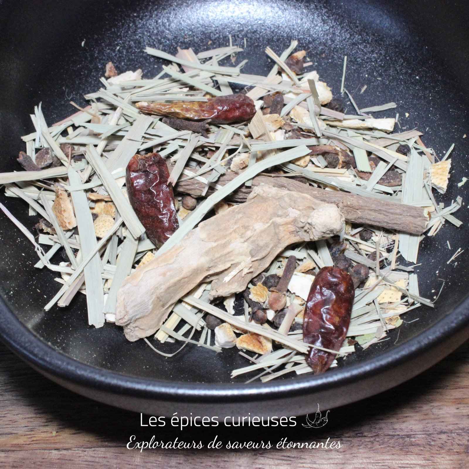 Préparation Diable Rouge pour Rhum Arrangé – Les épices curieuses Mélange d'épices et herbes séchées dans un bol noir, idéal pour infusions ou plats aromatiques.