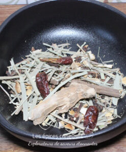 Assortiment d'herbes séchées et épices dans un bol noir, idéal pour préparer des infusions ou assaisonner des plats.