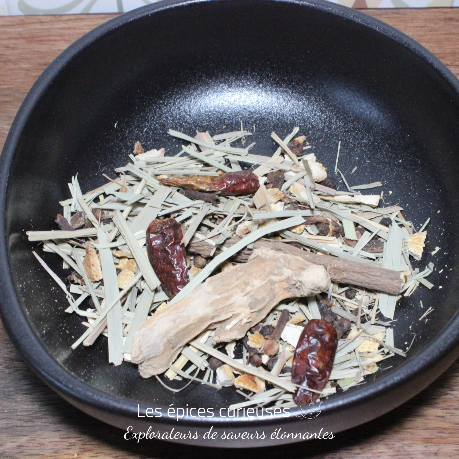 Préparation Diable Rouge pour Rhum Arrangé – Les épices curieuses Assortiment d'herbes séchées et épices dans un bol noir, idéal pour préparer des infusions ou assaisonner des plats.