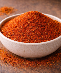 Bol de piment de Cayenne moulu, épice rouge vif sur une table en bois, idéal pour rehausser la saveur des plats.
